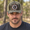 Man wearing a Thin Red Line Tactical Mossy Oak Bottomland camouflage trucker hat outdoors